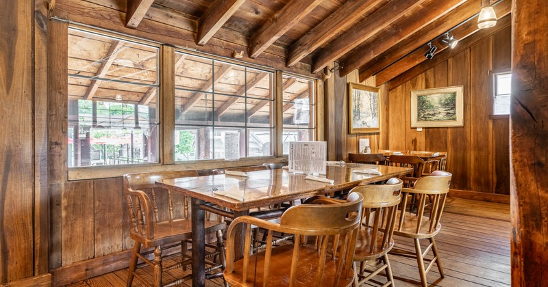 Interior, dining area, wooden tables for six and four, wooden walls and flooring, framed paintings