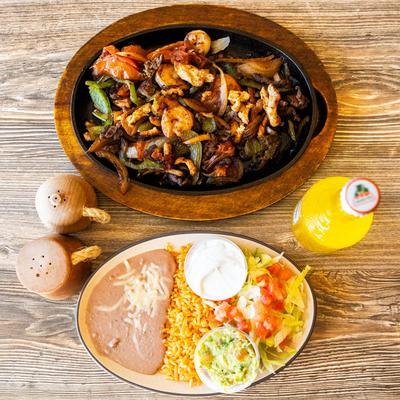 Trio Skillet served with sides of rice, beans and salad and a drink.