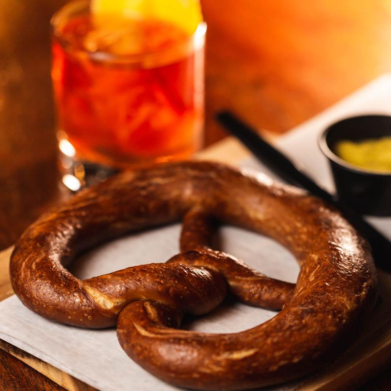 Warm pretzel served with a dip, accompanied by a glass of drink