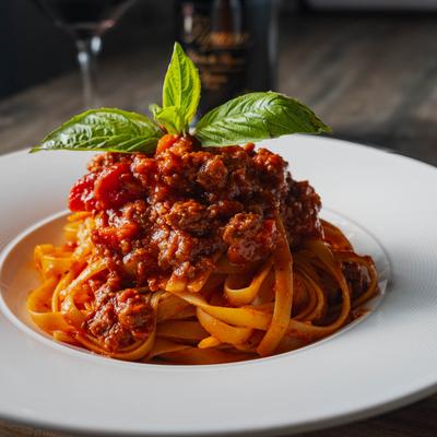 Fettuccine Bolognese with a mint sprig garnish, side view.