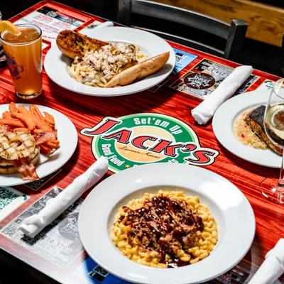 Assorted dishes on a table including pasta, mac and cheese, blackened salmon and drinks.