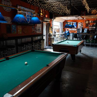 Pool tables with overhead lighting in a bar.