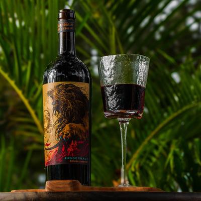 Juggernaut bottle and glass resting in front of palm branches.