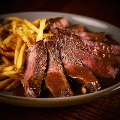 Grilled and sliced steak served alongside fries, close-up.