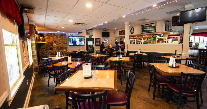 Dining area  with numerous tables and chairs, and a stone wall