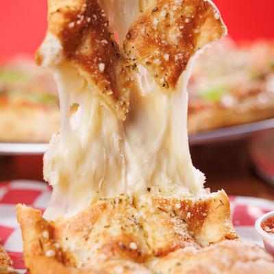 Close-up of a gooey cheese pull from cheese bread.