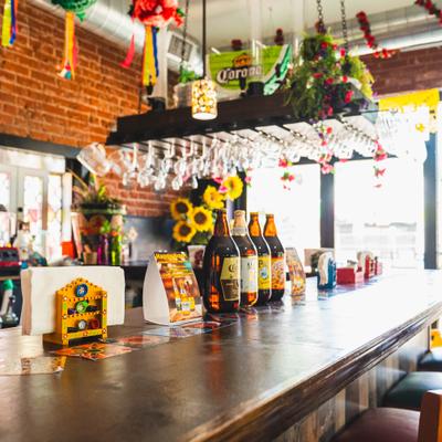 Interior featuring a wooden bar with bottles of beer lined up and various decotations.