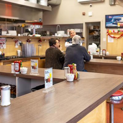 Interior, seating spaces, a couple of seated guests and a staffer.