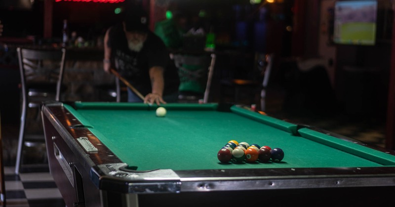 Interior, pool table and guest playing the shoot