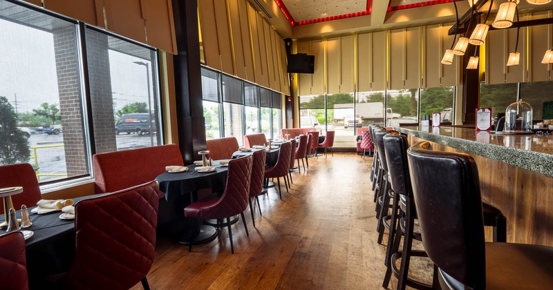 Interior featuring a bar, set tables, and large windows