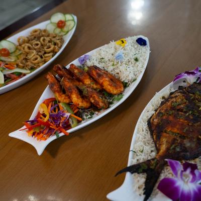 Grilled shrimp served with rice, alongside other dishes.