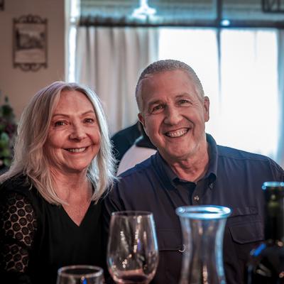 Two people smiling together at a wine table.