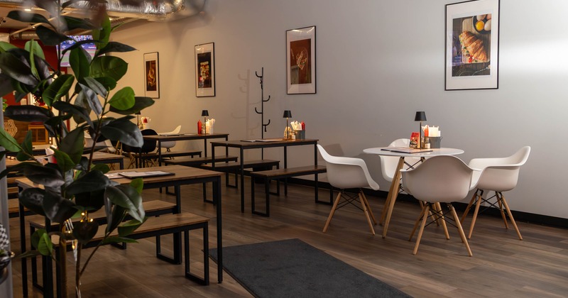 Modern dining area with wooden tables, white chairs, and framed pictures on the walls