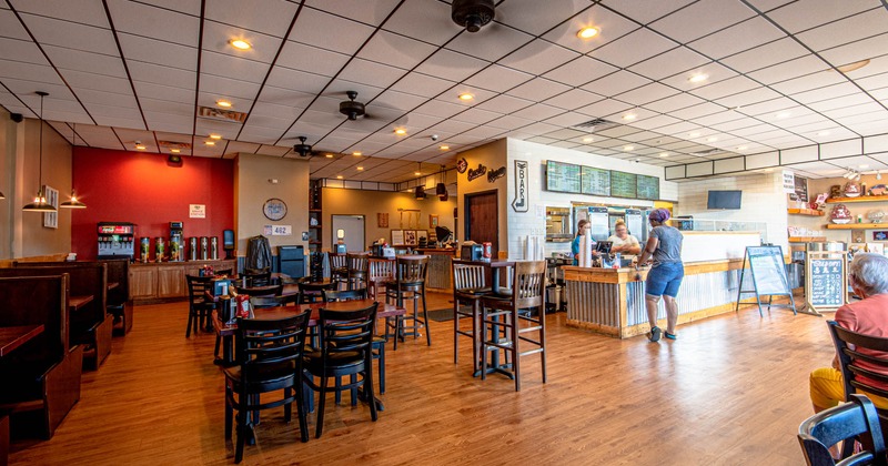 Interior, dining area and food order counter with staff serving a guest