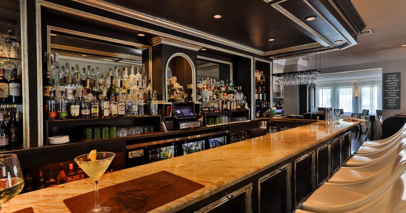 A stylish bar with a marble countertop and shelves stocked with liquor bottles
