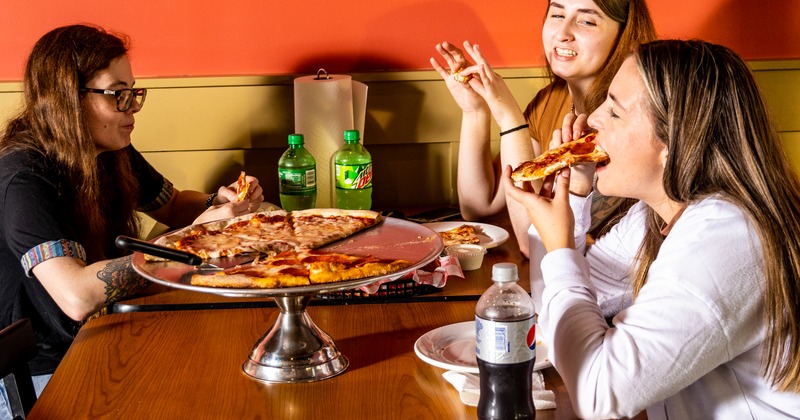 Interior, guests enjoying pizza and soft drinks at a table