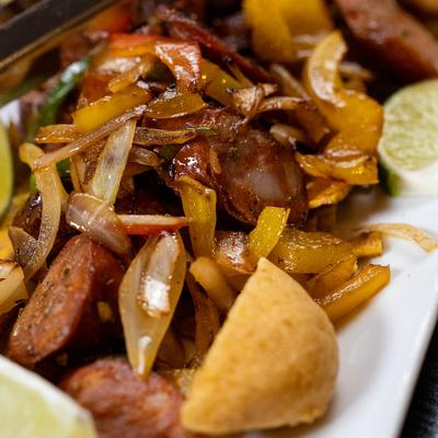 Close-up view of sauteed Colombian sausage with onions and peppers.