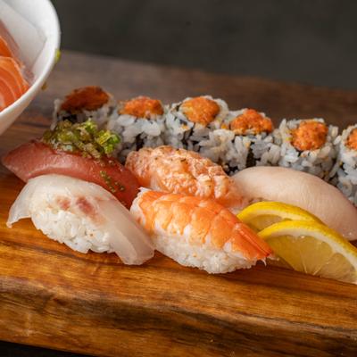 Assorted nigiri and sushi rolls on a wooden board.