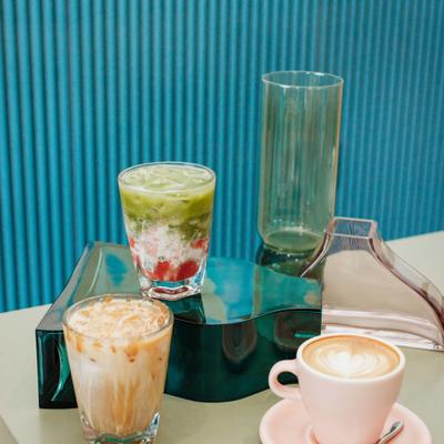 Iced strawberry matcha latte, iced caramel coffee, and hot latte on a modern cafe table.