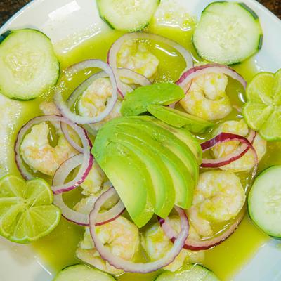 Raw Jumbo Shrimp cooked in lime sauce, with red onions, cucumber, and avocado.