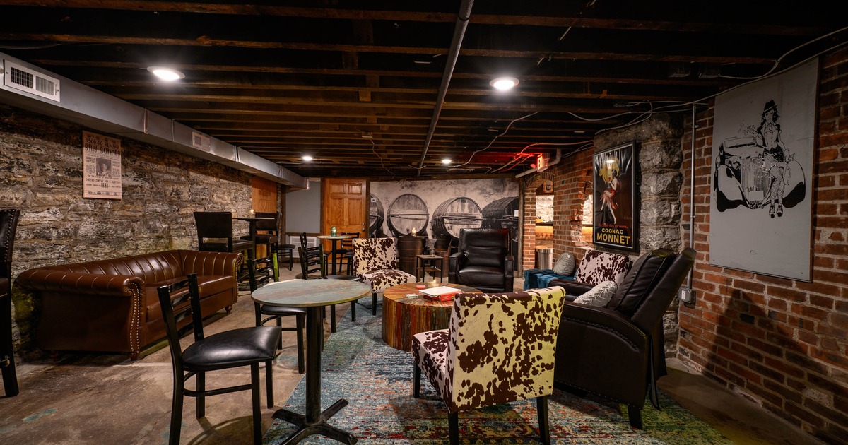 Interior, seating area, three seater leather sofa, armchairs with tables, stone and brick walls