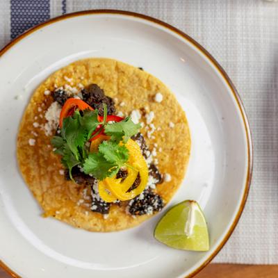 Carne asada taco served on tortilla with peppers.