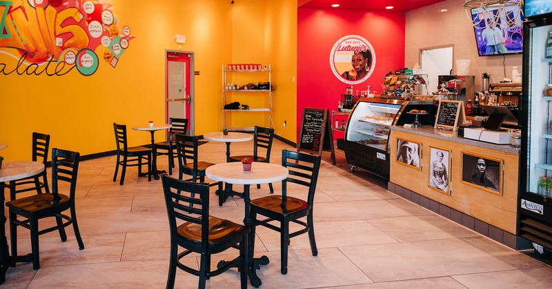 Interior, round tables for two, order counter, orange and red walls with mural art