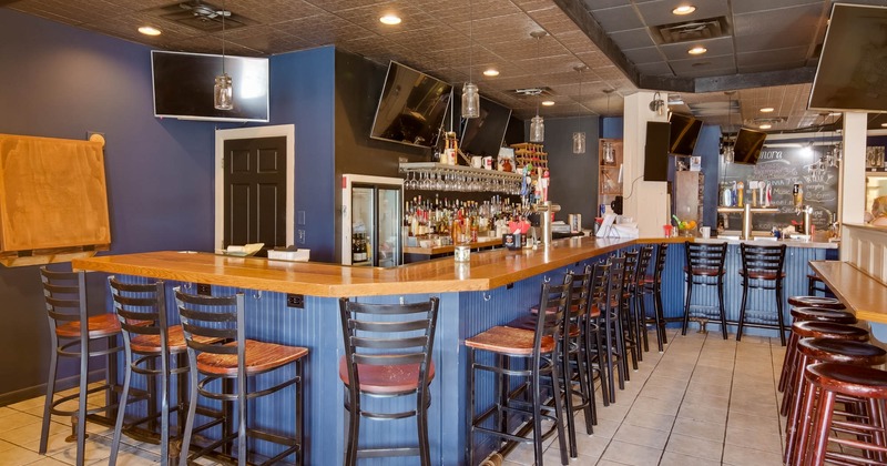 Interior, bar with stools, drink and glass rack behind the bar, blue wooden bar coating