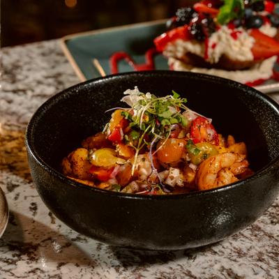 Bowl of garlic shrimp with onion, cherry tomatoes and microgreens.