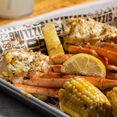 Steamed crab legs with corn on the cob and lemon wedges.
