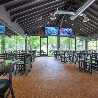 Bright interior with large windows, tables, chairs, and TVs.