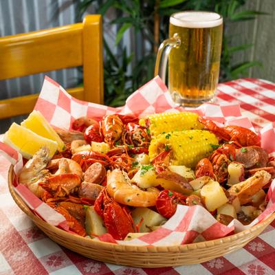 Cajun seafood boil with crawfish, shrimp, sausage, potatoes, corn, and a beer.