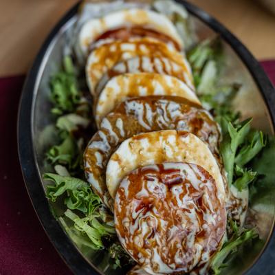Caprese salad featuring slices of tomato and mozzarella served on a bed of arugula.