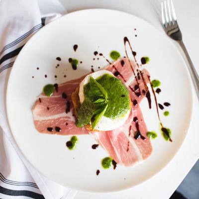 Burrata served with prosciutto slices, drizzled with balsamic and pesto.