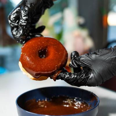 Chocolate-glazed donut being dipped into a bowl of chocolate icing.