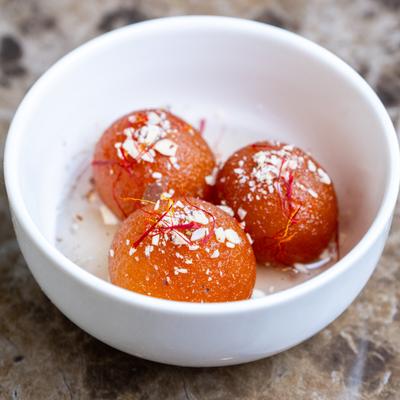 A white bowl with gulab jamun.
