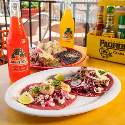 Tacos and enchilada plate, served with sodas and condiments.