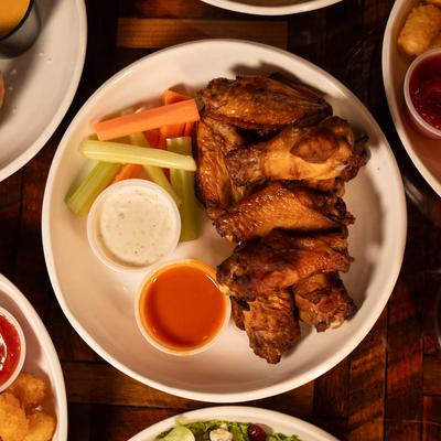 Oven Roasted Wings plate surrounded by assorted food plates, top view.