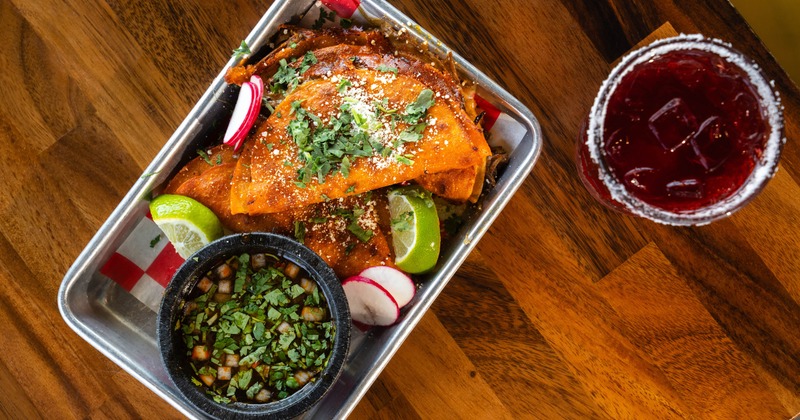 Quesabirria tacos served with a side of consommé, and a red drink