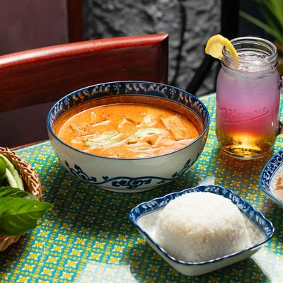 Massaman Curry on a table with rice and a Butterfly Pea Lemonade.
