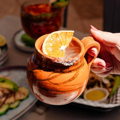 Cantarito drink in hand illuminated by sunlight.