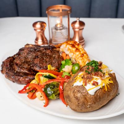 Cowboy rib eye and lobster tail, served with cooked vegetables.