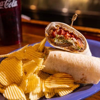 Texas Burrito cut in half and served with a side of potato chips.