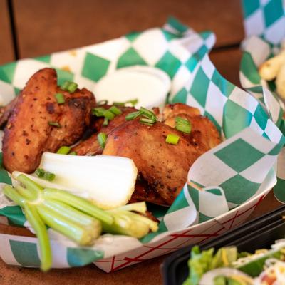 Dry Rub Wings served in a basket lined with checkered paper with dip on the side.