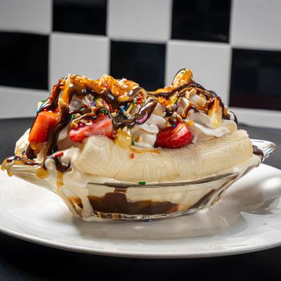 Banana Split featuring ice cream, whipped cream, fresh strawberries, and pineapple chunks.
