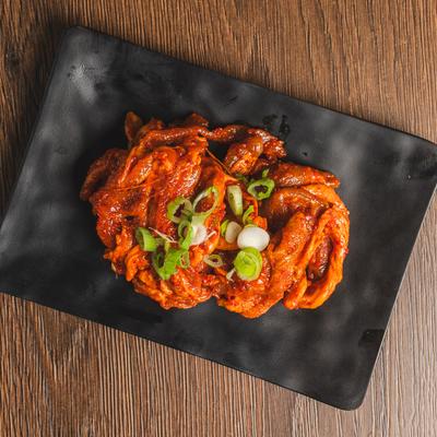 Raw Spicy Pork Bulgogi garnished with chopped green onion.