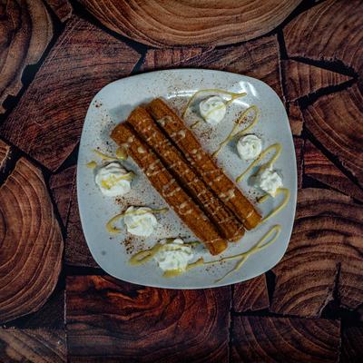 Churros served on a plate with whipped cream garnish.