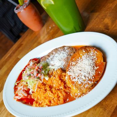 Combo plate with enchilada and chile relleno, served with rice, Pico de Gallo, and beans.