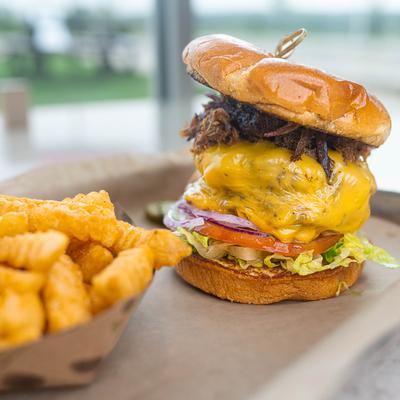Double cheeseburger, with pulled pork, lettuce, tomato, onion, pickles, and fries.