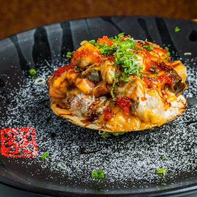 Flaming Scallop appetizer, served on a black plate.